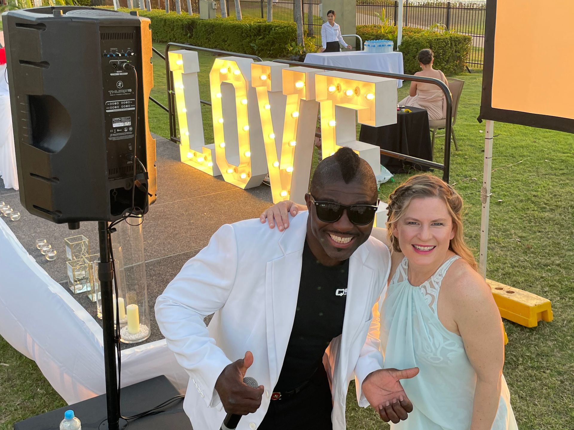 A man and woman smile, posing by a 