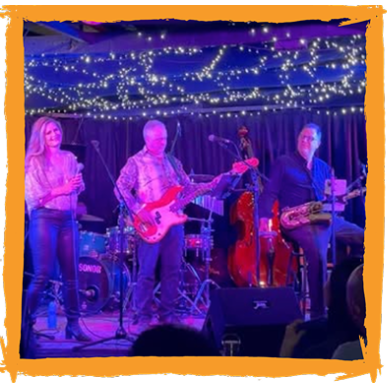 Band performing on stage under fairy lights: singer, bassist, saxophone player, drummer, upright bass.