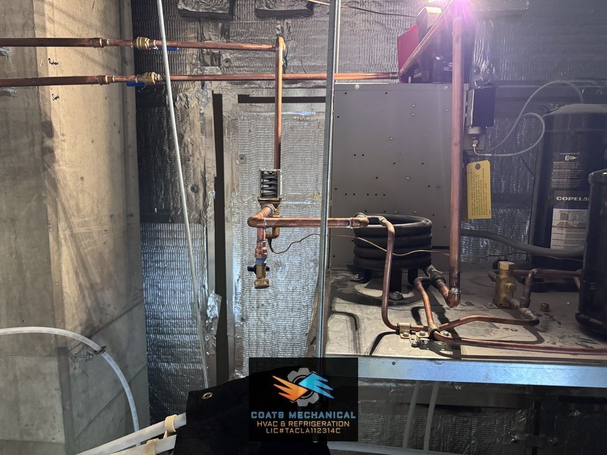 Industrial basement with exposed pipes, metal tank, and equipment under bright utility light