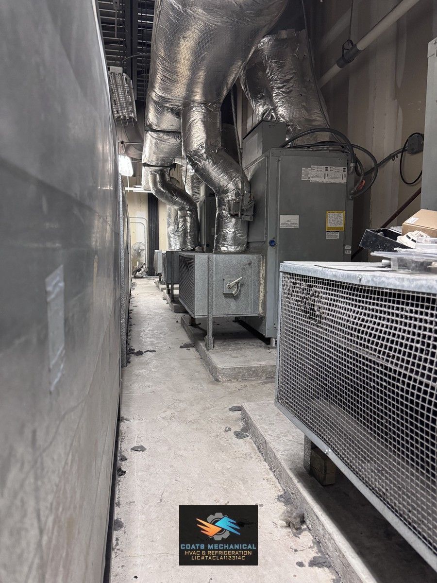Narrow industrial corridor with large metal ducts, equipment units, and a concrete floor. YMCA Northwest Austin, TX