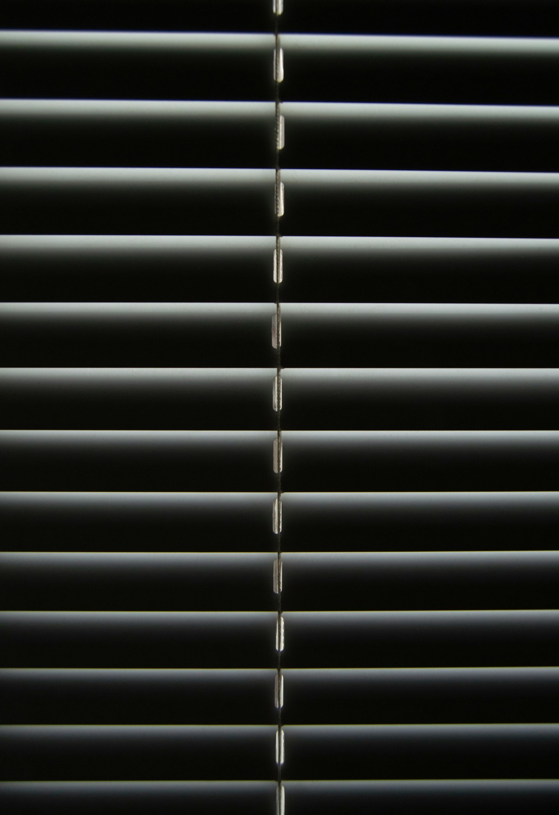 Horizontal window blinds, closed, casting shadows.