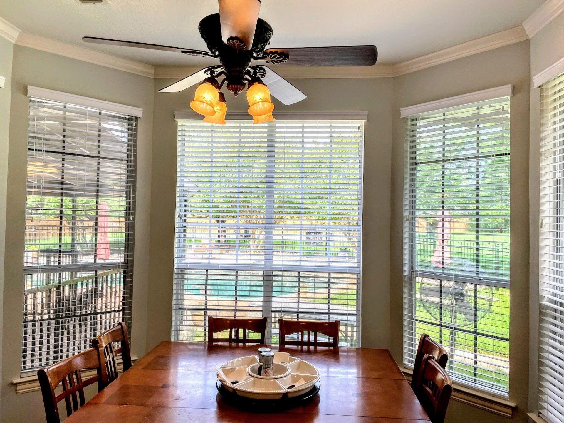a dining room with a table and chairs and a ceiling fan custom-window-blinds Love is Blinds Georgia.