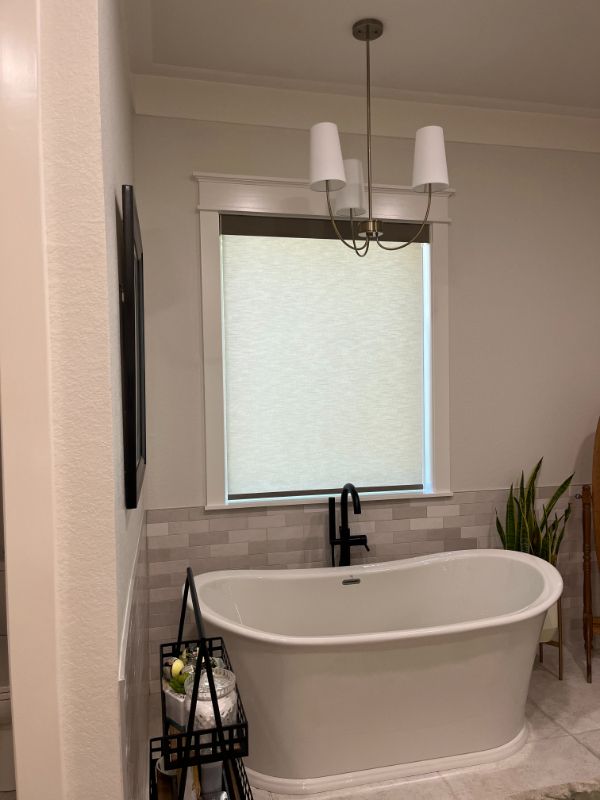 Love is Blinds GA: A bathroom with a bathtub and a window with white roller shades.