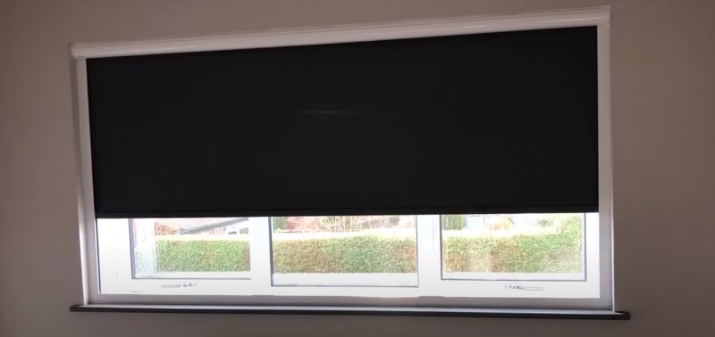 A window with a black blind on it in a room.