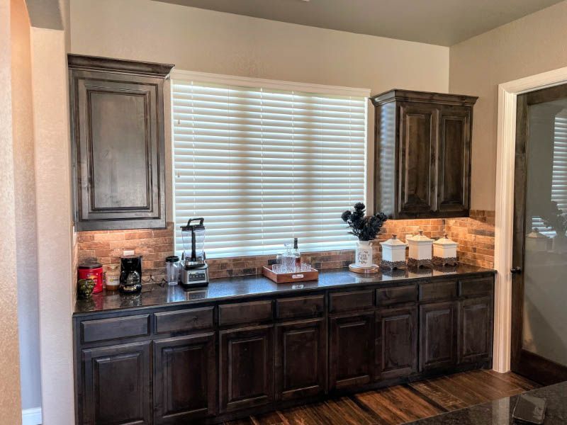 a kitchen with a lot of cabinets and a window window blinds above bar Love is Blinds Georgia blinds installation.