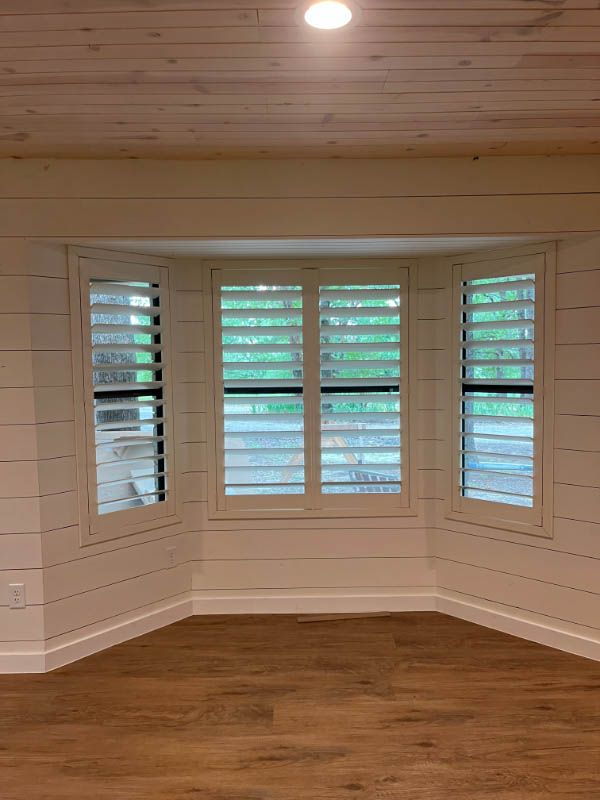 an empty room with a bay window and shutters on the windows custom shutter installation Love is Blinds Georgia.