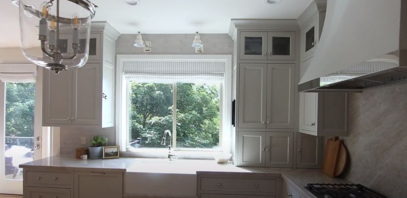 a kitchen with white cabinets , a sink , a stove and a window roman shades blinds solutions Love is Blinds Georgia.