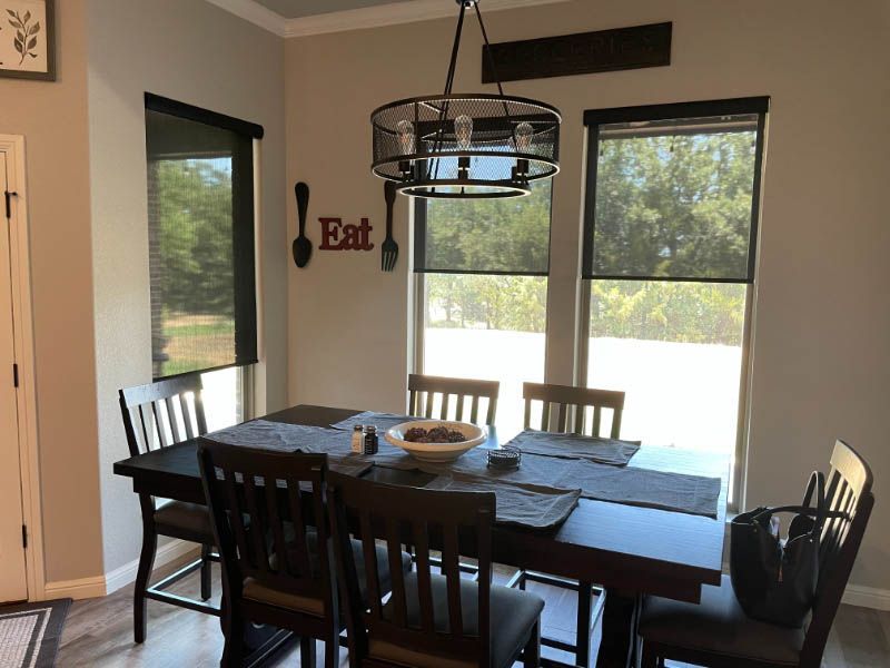 a dining room with a table and chairs and a sign that says eat. Roller shades dining room Love is Blinds Georgia