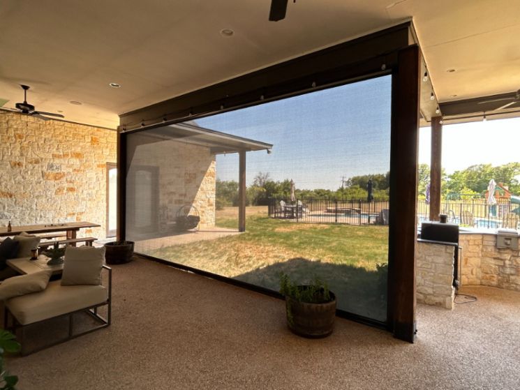 An outdoor kitchen area has exterior patio shades. 