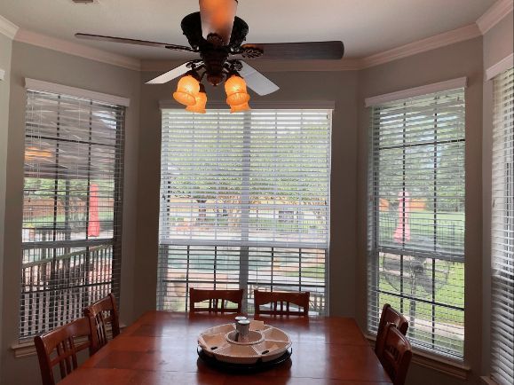 A dining room with a table and chairs and a ceiling fan
