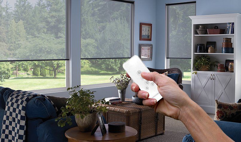 a person is holding a remote control in a living room with remote window shades Love is Blinds Georgia.