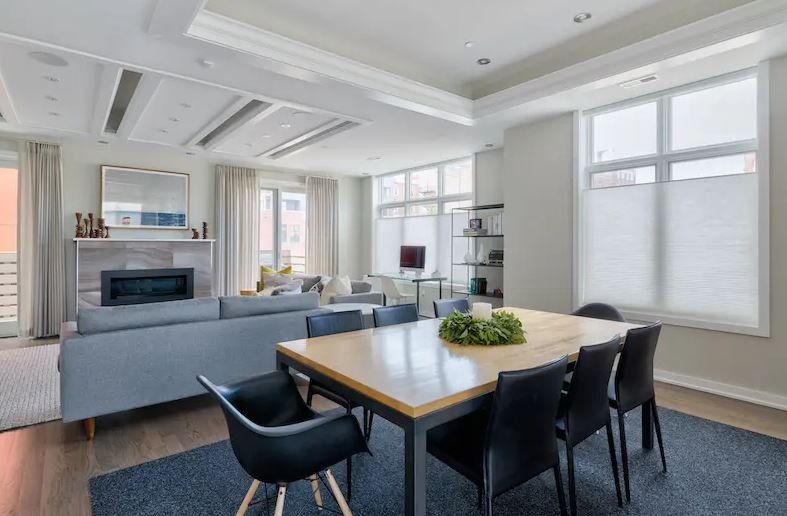 A living room with a dining table, chairs and a fireplace, top down bottom up shades on windows..