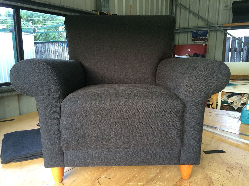 A Grey Chair With Orange Legs is on a Wooden Floor — Paulie's Upholstery in Cairns, QLD