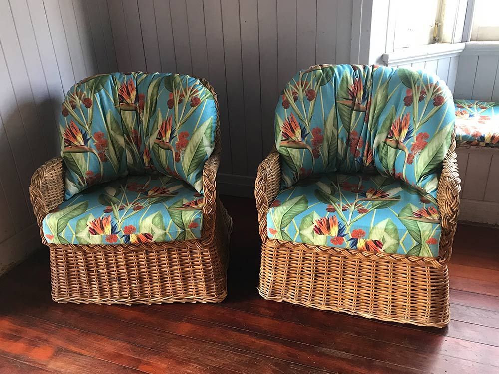Two Wicker Chairs Are Next to Each Other on a Wooden Floor in a Room — Paulie's Upholstery in Edmonton, QLD