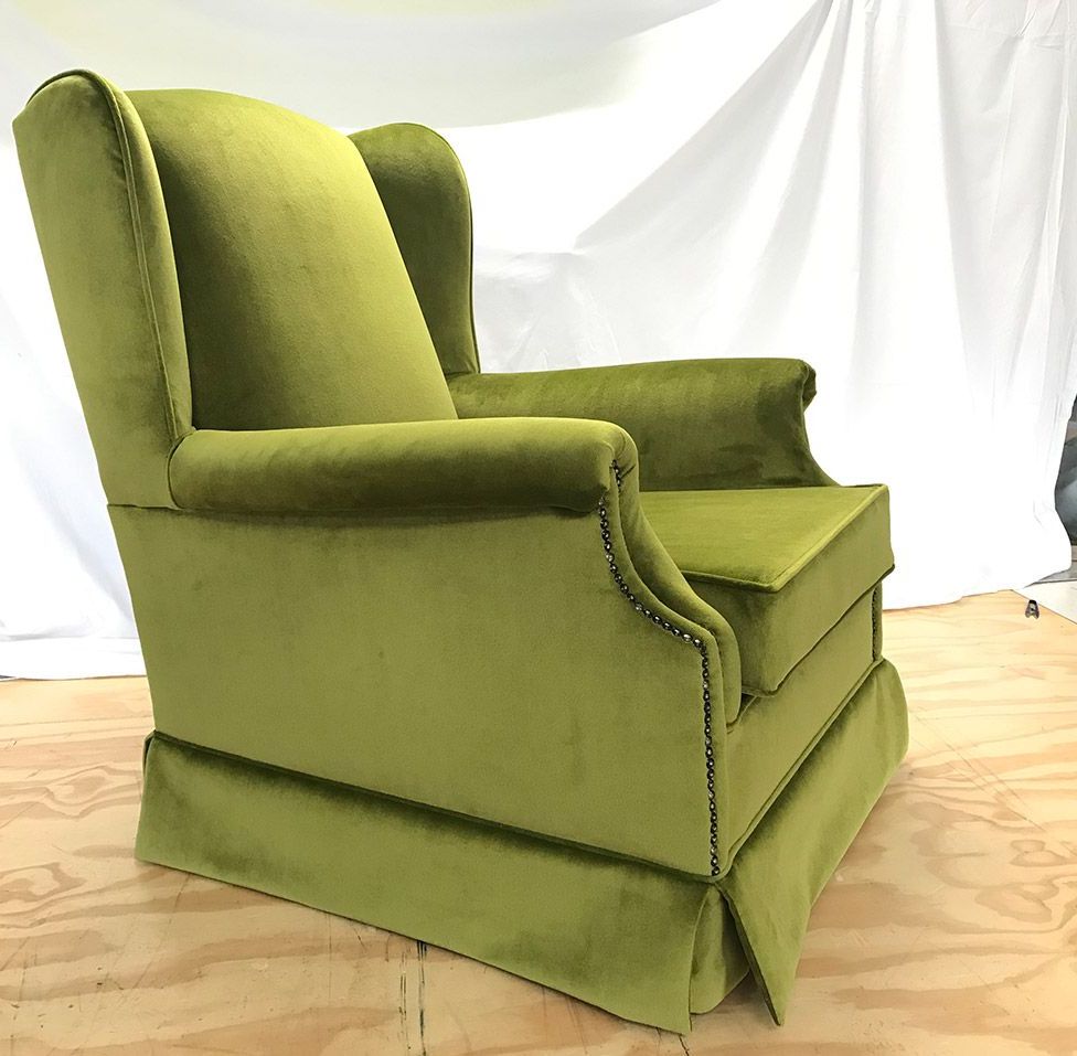 A Green Chair is on a Wooden Floor — Paulie's Upholstery in Edmonton, QLD