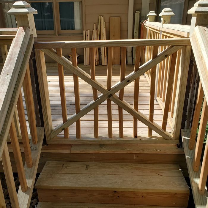 Wooden deck with gate, stairs, and railing.