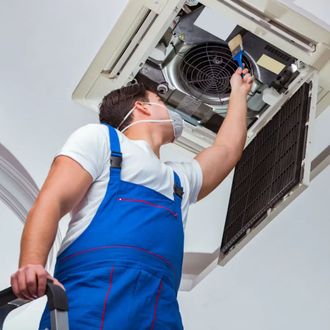 Doctor Air HVAC Corp. - A man wearing a mask is working on an air conditioner