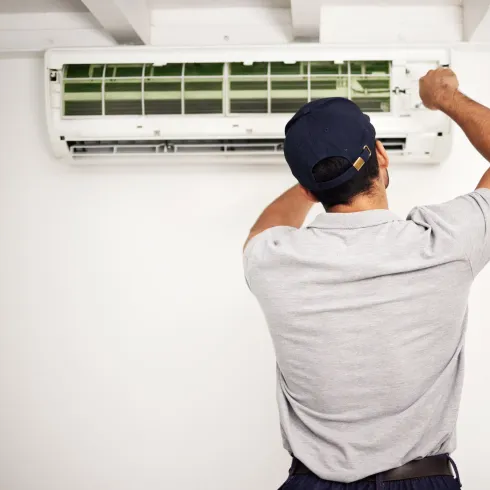 Doctor Air HVAC Corp. -  A man wearing a hat is working on an air conditioner
