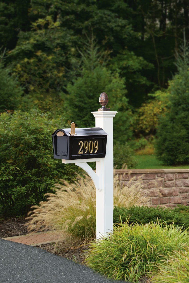 A black mailbox with the number 2909 on it is on a white post.