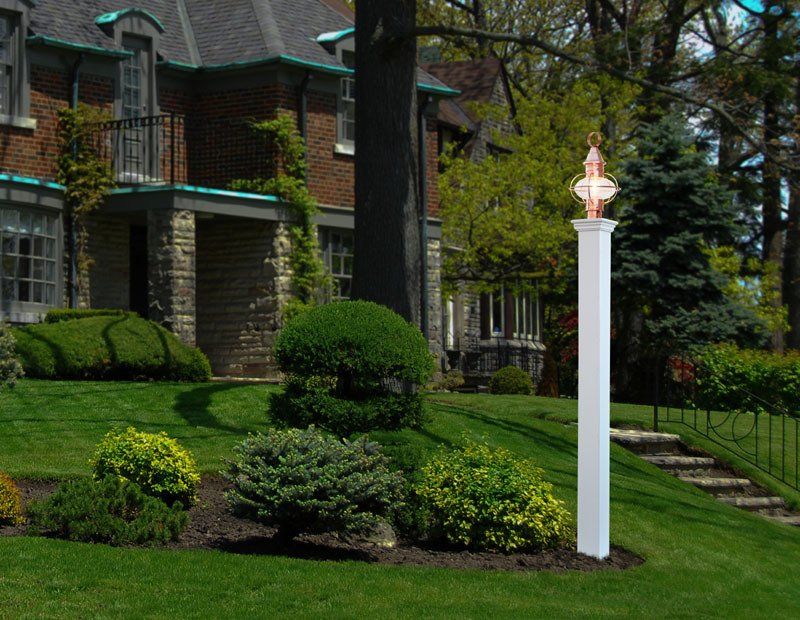 A white pole with a light on top of it in front of a house