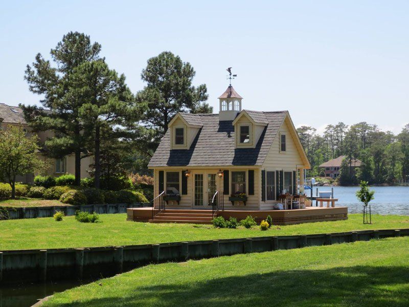 A small house sits on the shore of a lake