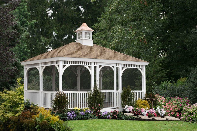 A white gazebo with a screened in porch in a garden