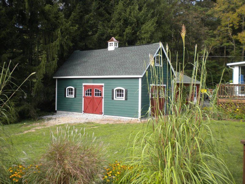 A green barn with a red door and shutters