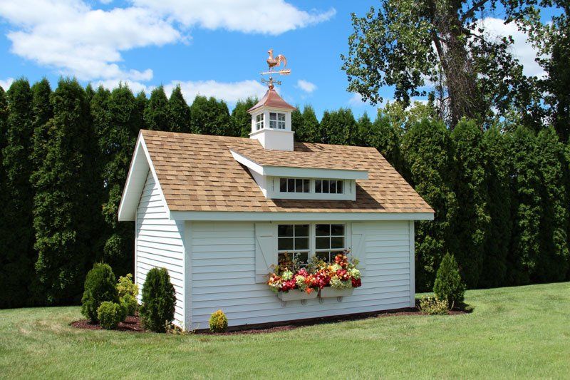 A small white house with a weather vane on top of it