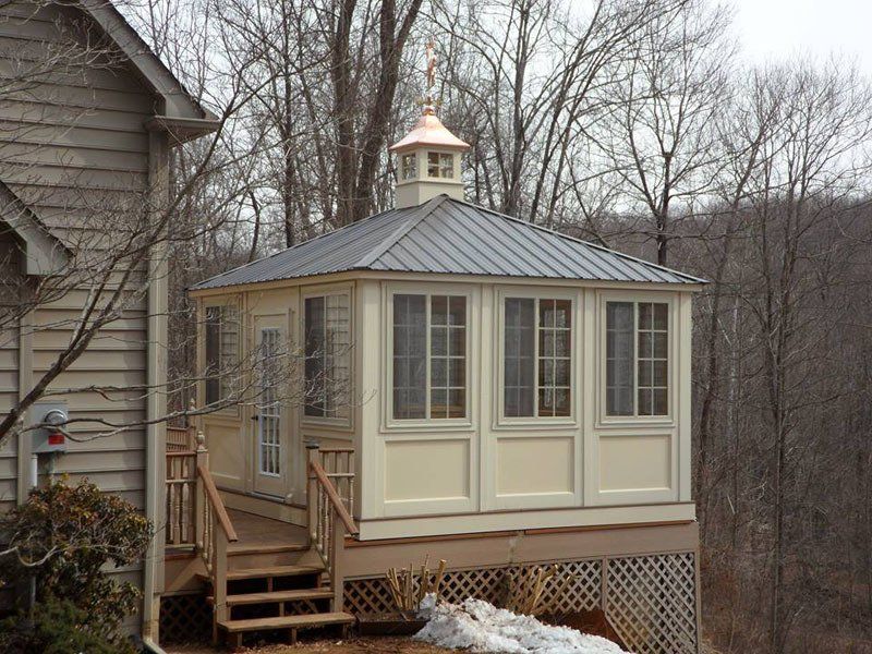 A gazebo with a copper roof sits next to a house