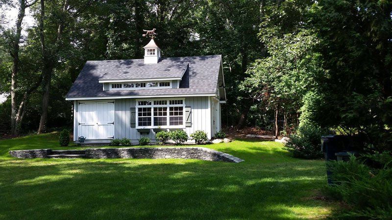 A small white house is sitting in the middle of a lush green field.