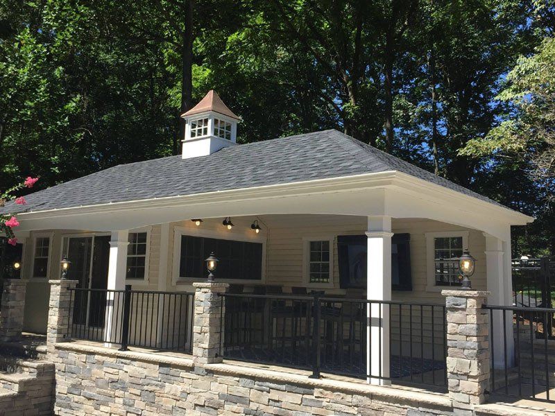 A large white house with a porch and a roof surrounded by trees.