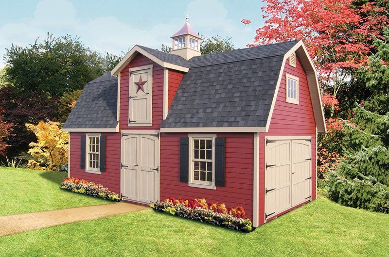 A red barn with a star on the door is sitting on top of a lush green field.