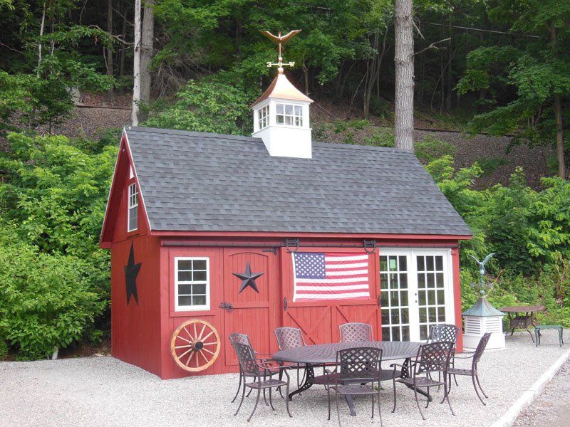 A red barn with a table and chairs in front of it