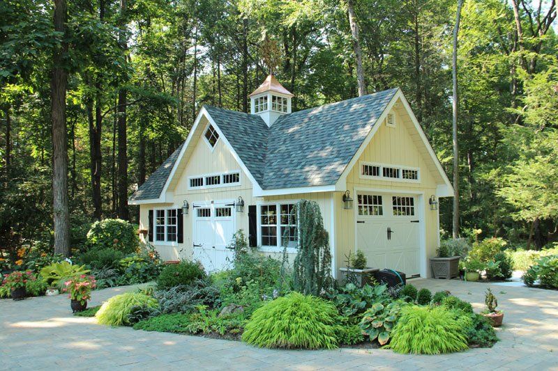A small yellow house with a black roof is surrounded by trees