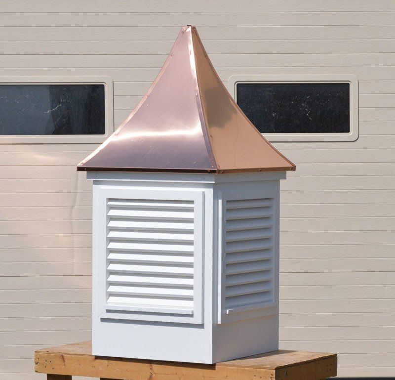 A white building with a copper roof and shutters