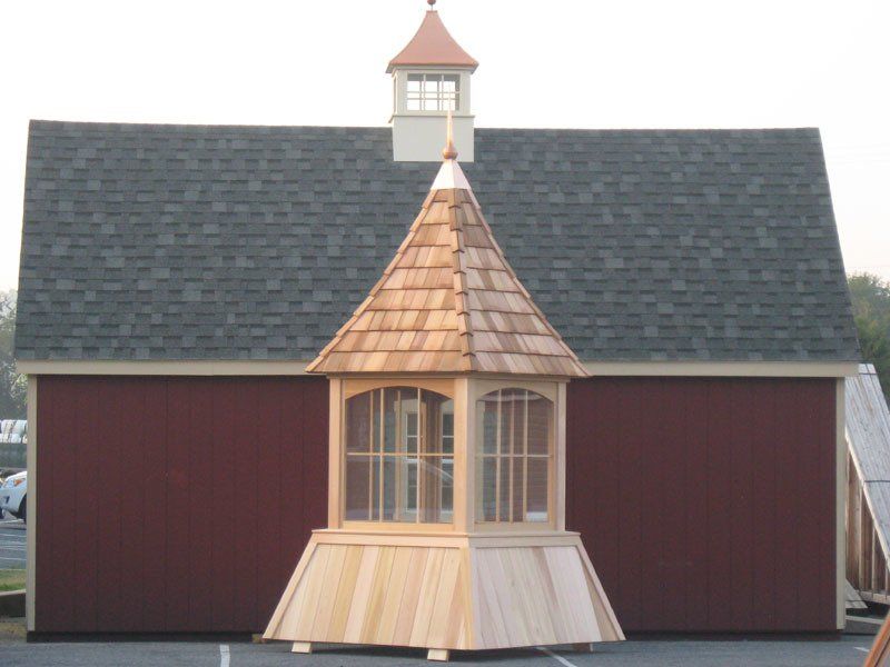A red barn with a wooden cupola on top of it