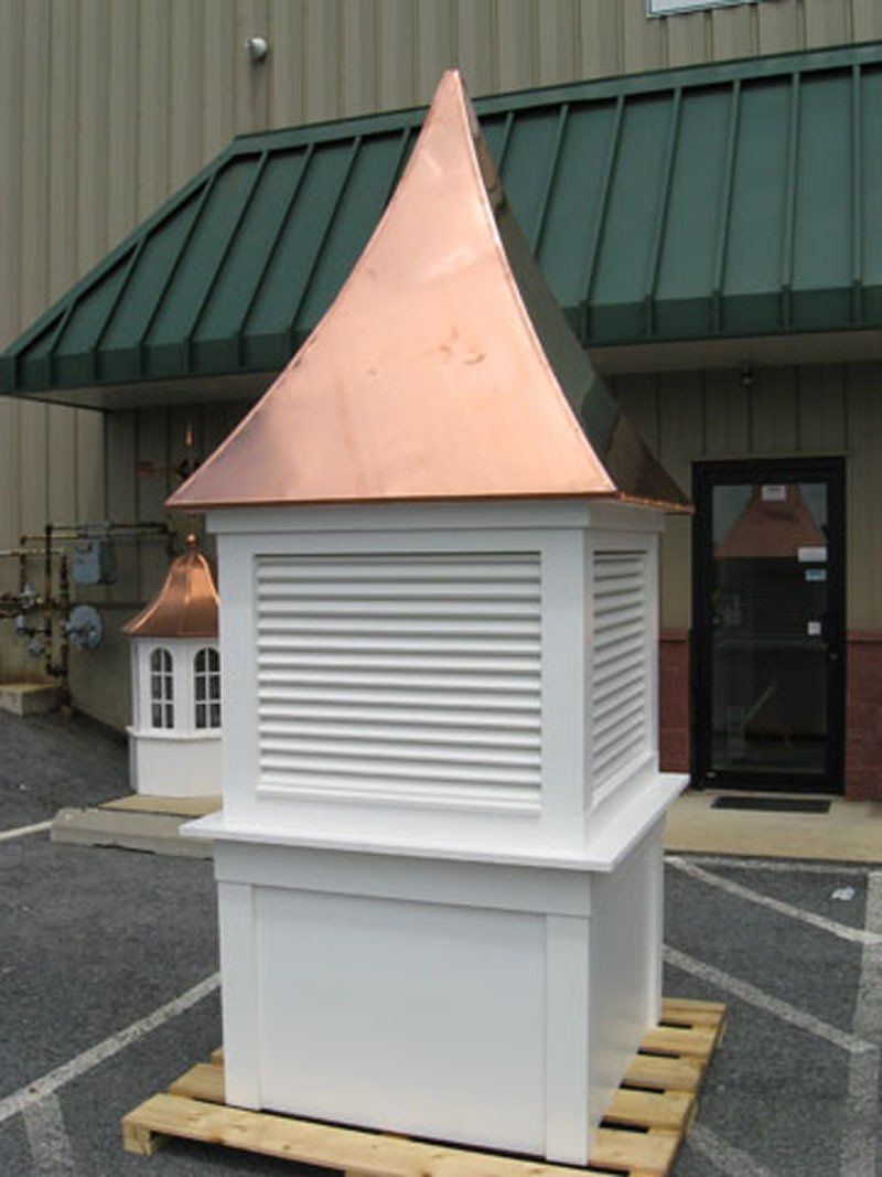 A white building with a copper roof sits on a wooden pallet