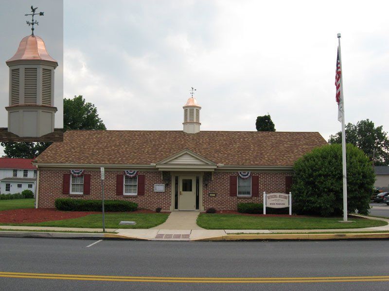 A brick building with a weather vane on top of it