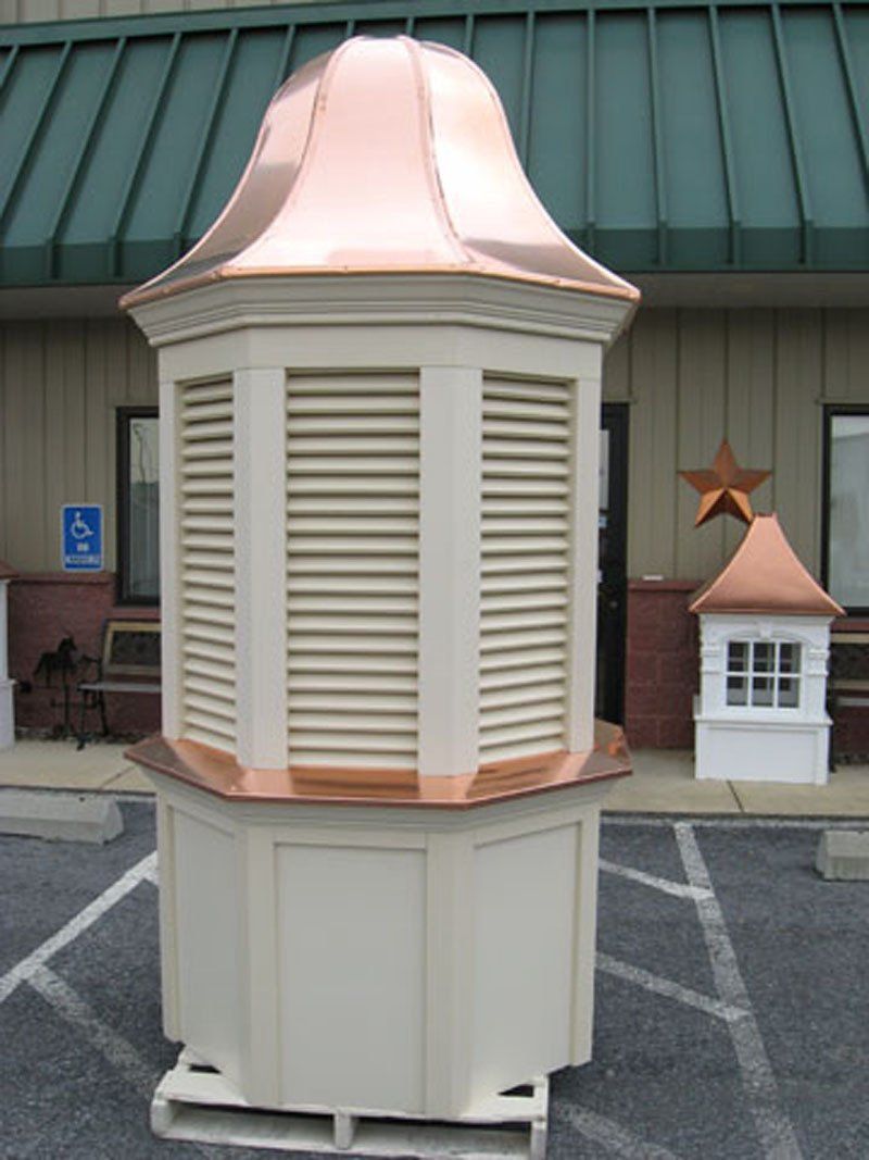 A white building with a copper roof sits in a parking lot