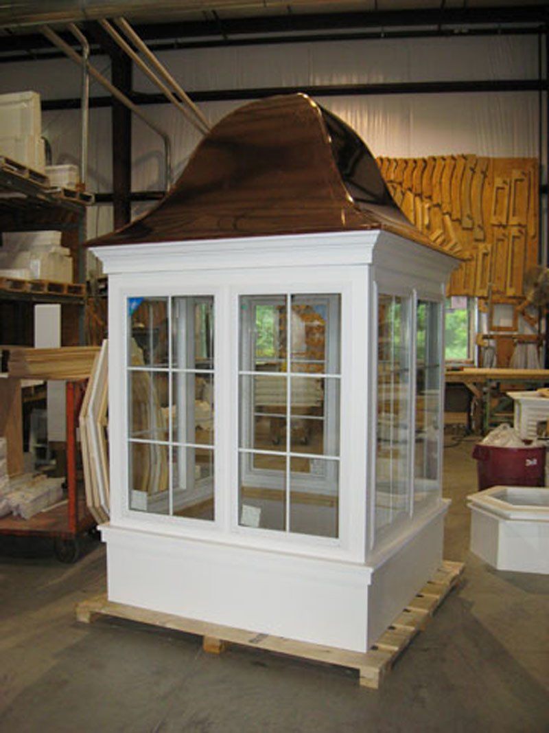 A white building with a copper roof is sitting on a wooden pallet.
