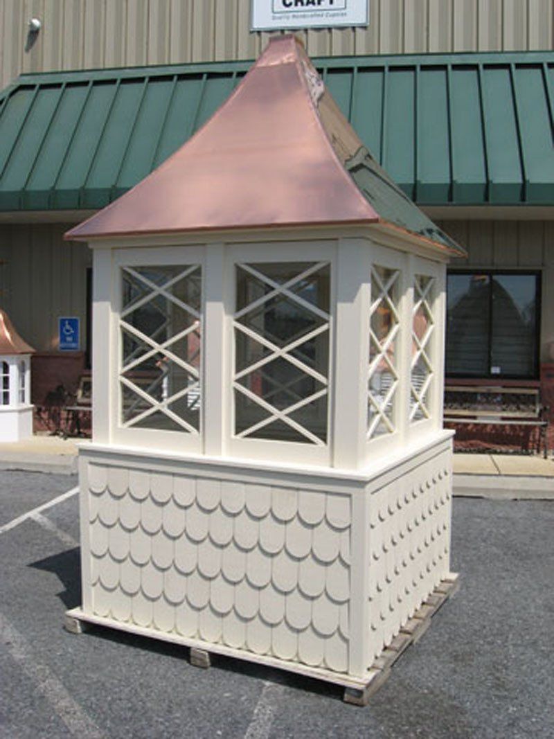 A white gazebo with a copper roof sits in front of a building that says craft