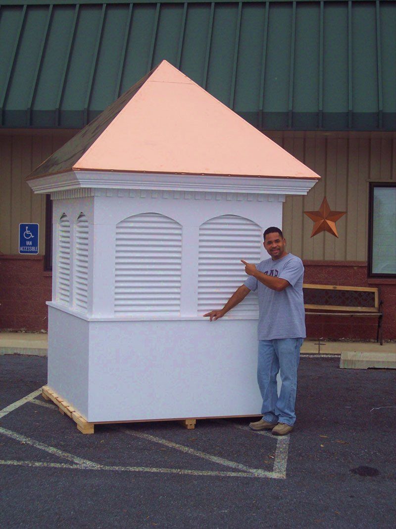 A man standing next to a white building with a copper roof