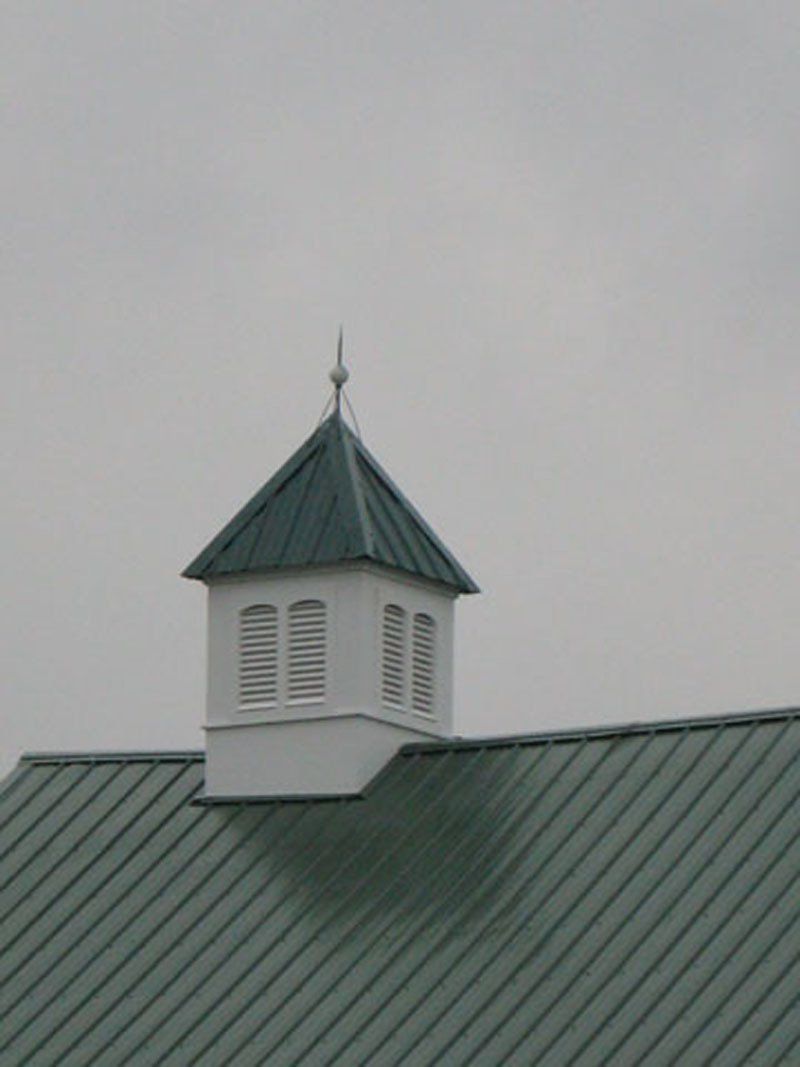A green roof with a white chimney on top of it.
