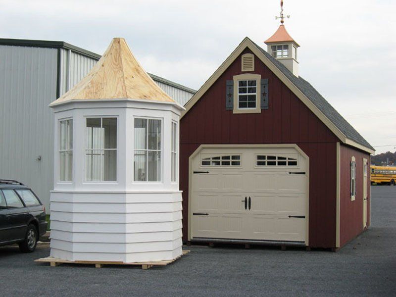 A red shed with a white bay window next to it