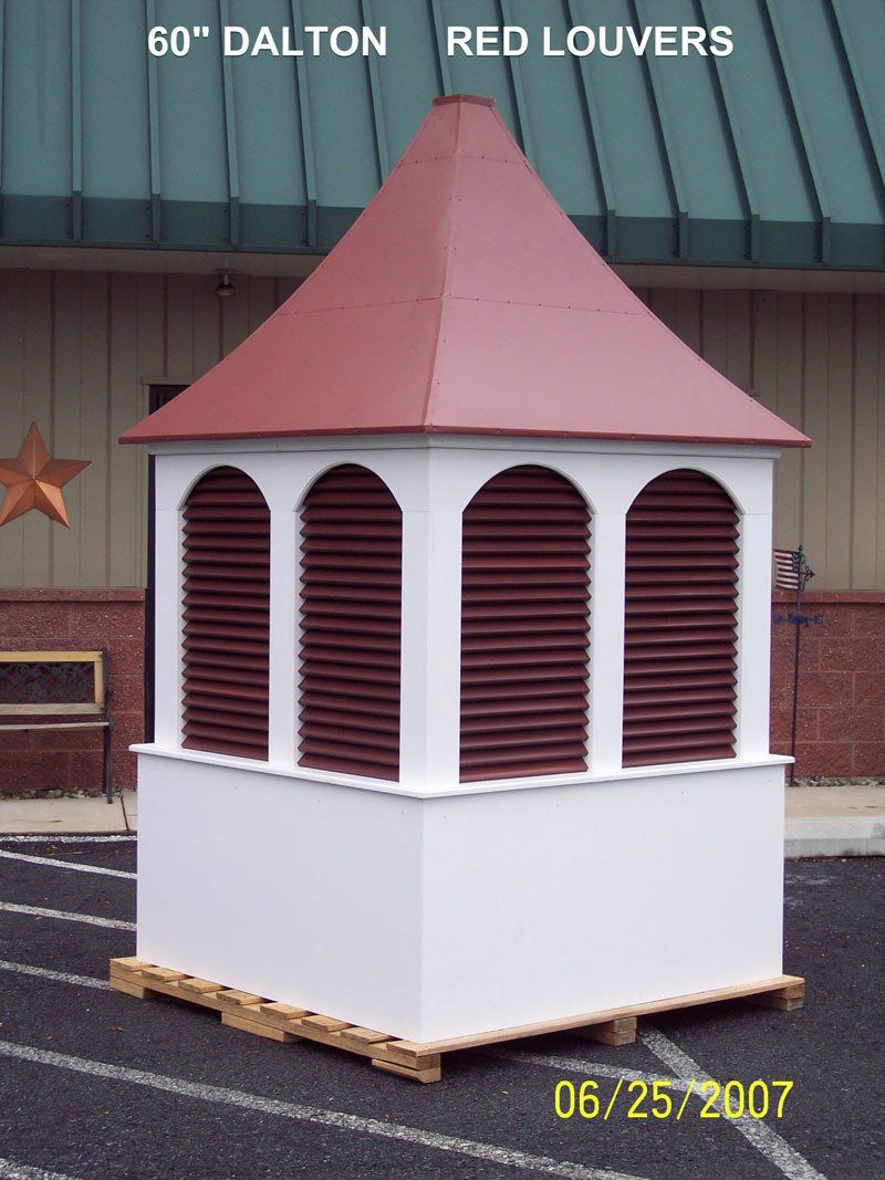 A white building with a red roof and red louvers
