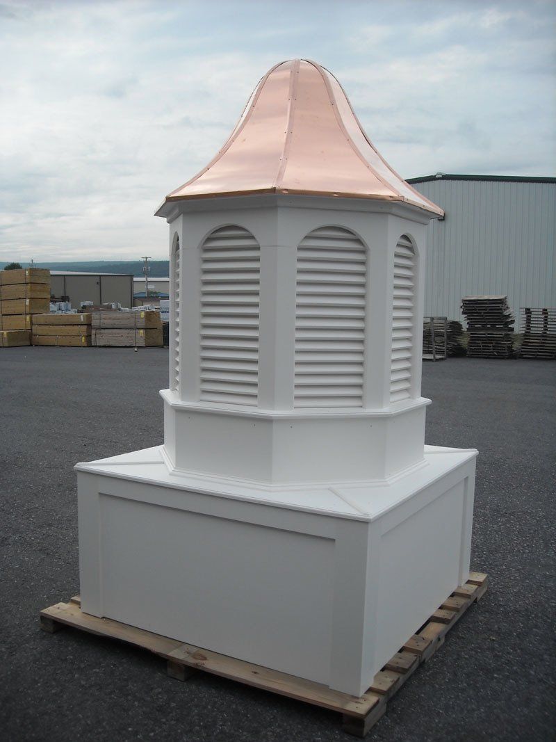 A white building with a copper roof is sitting on a wooden pallet.
