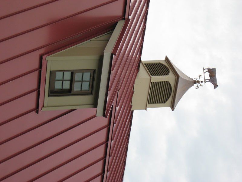 A red building with a weather vane on top of it