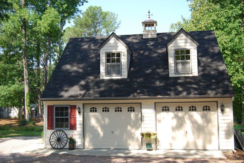A white garage with a black roof and red shutters