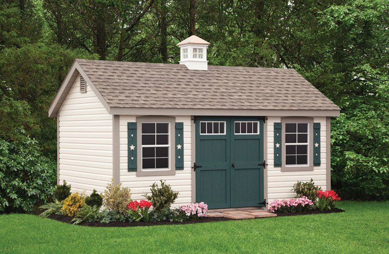 A white shed with a green door and shutters