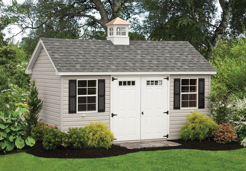 A white shed with a gray roof and black shutters